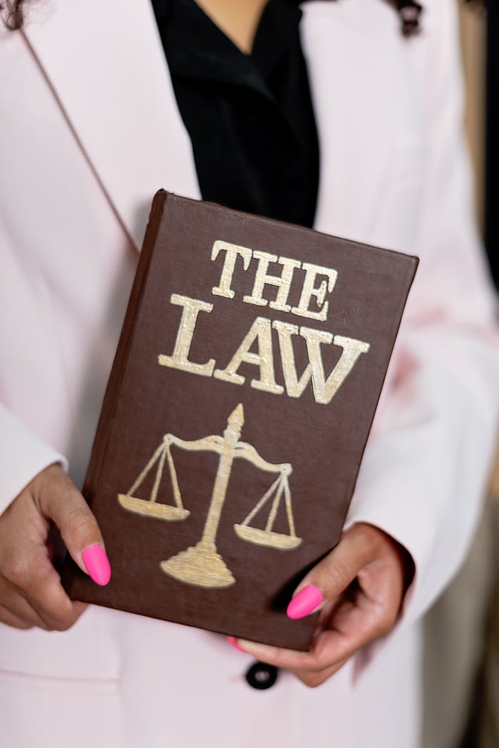 Close-up of a woman holding a law book with scales of justice, emphasizing legal themes.